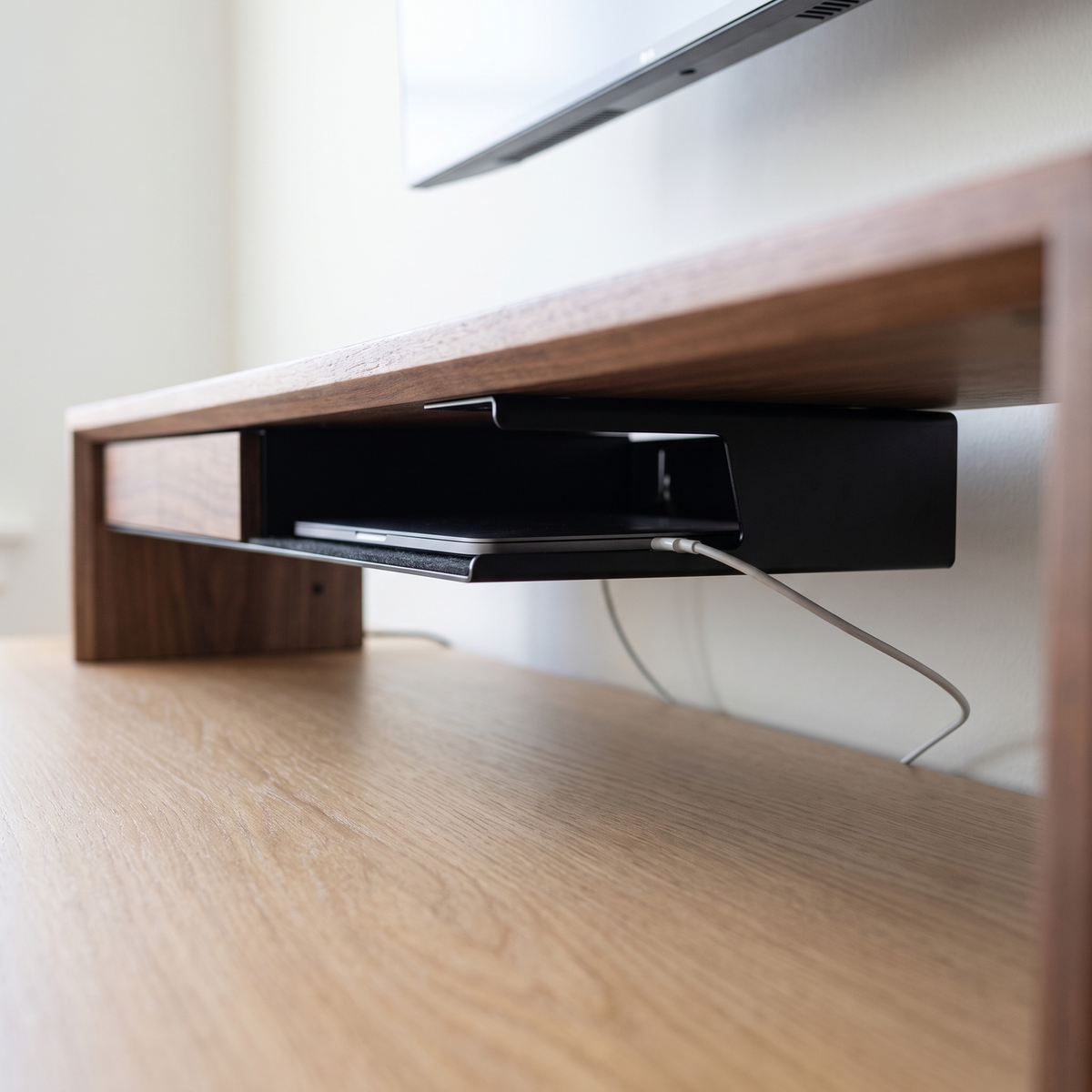 Side view of the Aldermere storage tray with a cable routed from a stored laptop