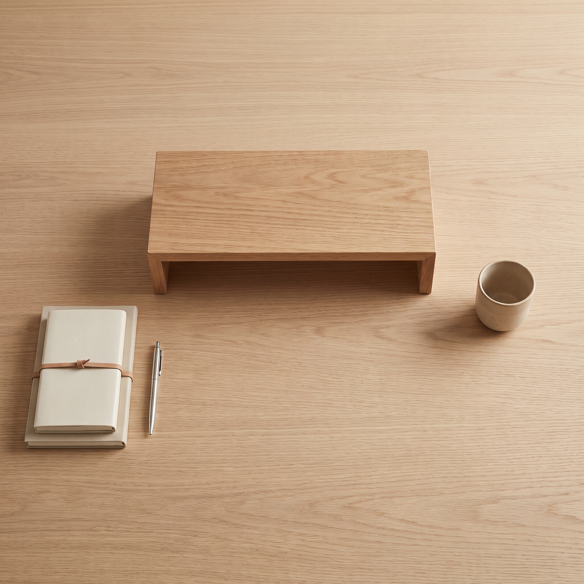 Overhead view of a tidy desk with a wooden monitor riser and notebook